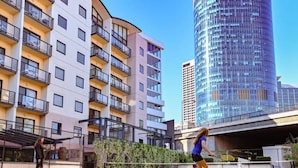 A tennis court with two players in action, surrounded by modern apartment buildings. - Walk to Elizabeth Quay | Pool & Parking (Perth)