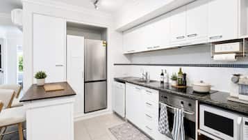 A modern kitchen with white cabinetry, a stainless steel refrigerator, a built-in oven, and a microwave.