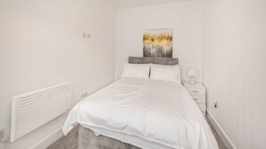 A bedroom with a bed, a nightstand, a wall-mounted artwork, and a radiator. - GuestReady - Fantastic Liverpool getaway (Liverpool)
