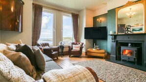 A cozy living room with a fireplace, comfortable seating, and a large window offering a scenic view.