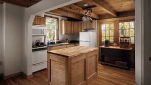 A kitchen with wooden cabinets, a central island, a stove, a microwave, and a refrigerator. - The Serenity Cabin | Firepit | Wineries | Hiking (Marshall)