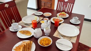 Uma mesa de café da manhã com torradas, cereais, frutas e suco.