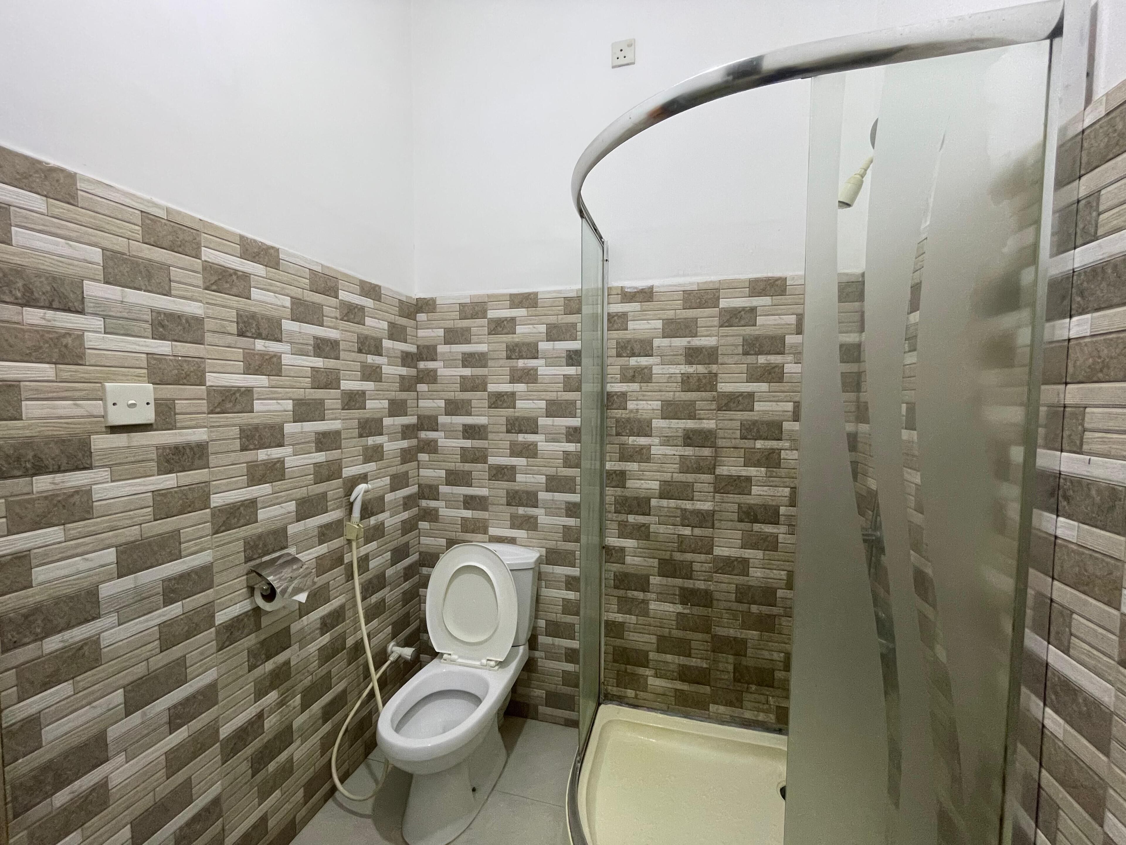 Une salle de bain comprenant des toilettes, une douche et un espace de douche vitré.