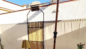 An outdoor patio with a wooden table, a yellow lamp, and a potted plant. - Domus Amelio - Country Rooms (Cinisi)