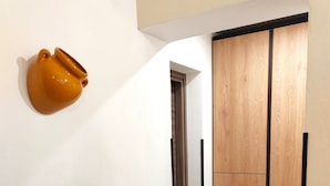 A hallway with a white wall, a wooden door, and a brown ceramic object. - Domus Amelio - Country Rooms (Cinisi)