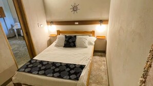 A bed with a wooden frame, a headboard with a sun decoration, and two bedside lamps. - Apartasuite near the sea - Coveñas (Coveñas)