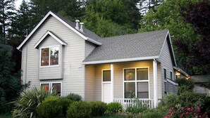 A two-story house with a front porch, a chimney, and a well-maintained garden.