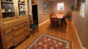 A dining area with a wooden cabinet, a dining table, chairs, and a patterned rug.