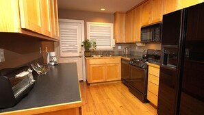 A kitchen with wooden cabinets, a black refrigerator, a stove, and a microwave.