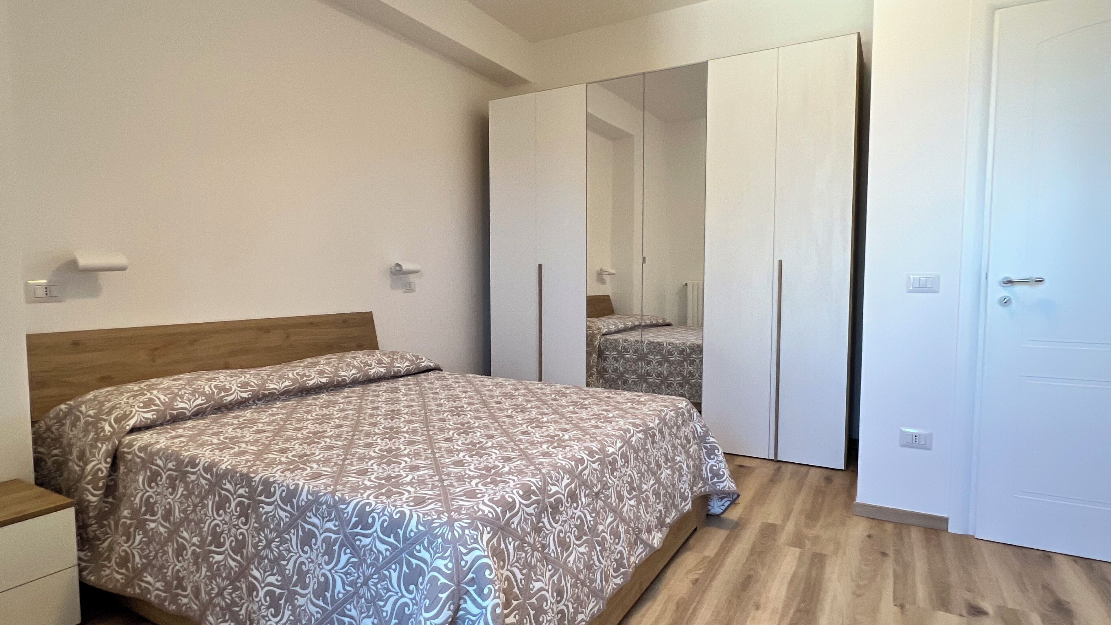 A bedroom with a wooden bed, a wardrobe, and a mirror.