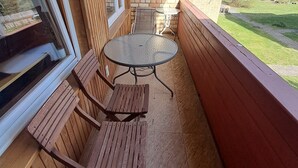A covered patio with a round table and wooden benches, a brick wall, and a view of a grassy area. - Cozy apt, 100m beach, AC, workstation, balcony, backyard, self check-in, yogamat (Jūrmala)