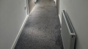 A narrow hallway with a white door at the end, a skylight above, and a radiator on the right.