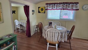 A dining area with a round table, chairs, a window with curtains, and a clock on the wall. - Offut Lake!  Pet friendly cottage with lake access..  Bring your fishing rod! (Tenino)