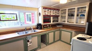 A kitchen with a wooden countertop, a sink, a coffee maker, and cabinets. - Offut Lake!  Pet friendly cottage with lake access..  Bring your fishing rod! (Tenino)