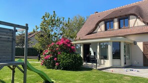 A residential property with a covered patio, a play area with a slide, and a well-maintained lawn. - Ma belle Normande entre terre & mer - My beautiful Normandy between land and sea (Saint-Léonard)