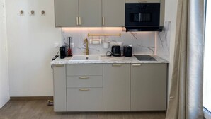 Una cocina compacta con gabinetes grises, un microondas negro, un fregadero y una encimera de mármol.