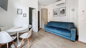 Una sala moderna con un sofá azul, sillas blancas y una pequeña mesa redonda.