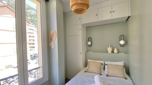Un dormitorio con cama, ventana y ventilador de techo.