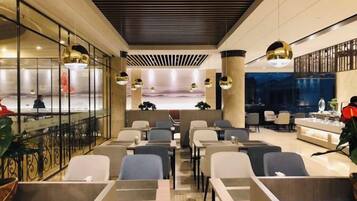 A modern hotel lobby with a reception desk, seating area, and a view of the cityscape.