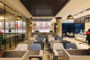 Un moderno vestíbulo de hotel con una recepción, zona de estar y vistas a la ciudad.