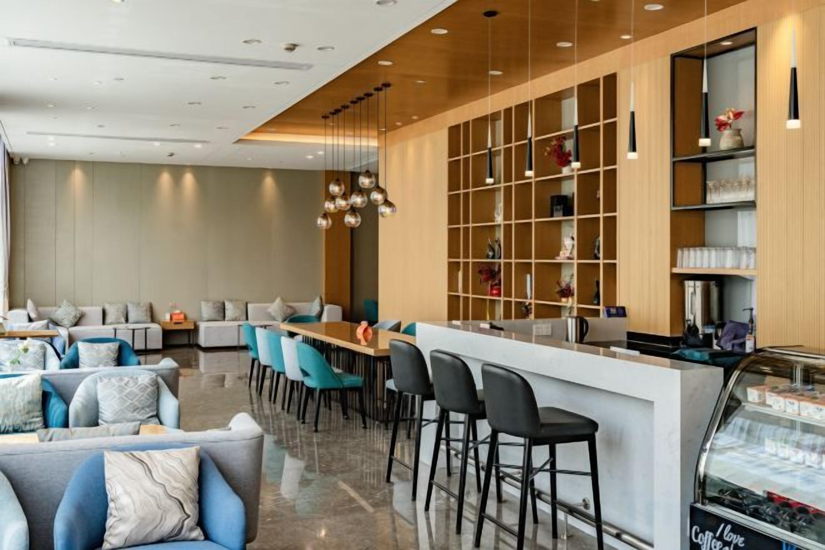 A modern hotel lobby with a seating area, a bar, and a counter.