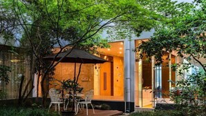 A modern building with a glass entrance, outdoor seating, and lush greenery. - Jingyuan Shuizhuang Hotel (Shanghai)
