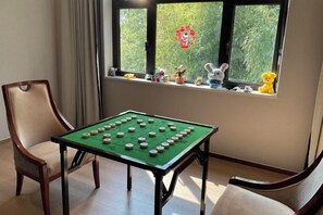 A room with a foosball table, two chairs, a window with toys on the sill, and a view of greenery outside. - Jingyuan Shuizhuang Hotel (Shanghai)