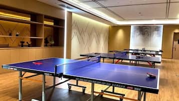 A room with ping pong tables, a wooden floor, and a wall with a geometric pattern.