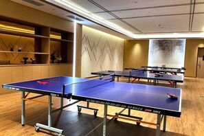 A room with ping pong tables, a wooden floor, and a wall with a geometric pattern. - Jingyuan Shuizhuang Hotel (Shanghai)