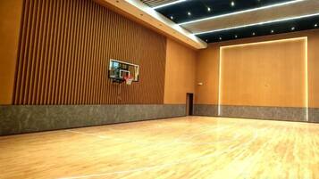 A basketball court with a wooden floor, a basketball hoop, and a wall with vertical wooden slats.