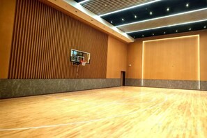 Una cancha de baloncesto con piso de madera, un aro de baloncesto y una pared con listones verticales de madera.
