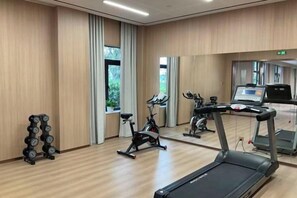 Un gimnasio con cintas de correr, bicicletas estáticas y máquinas de pesas.