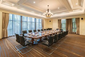 A conference room with a long table, multiple chairs, and a chandelier. - Jingyuan Shuizhuang Hotel (Shanghai)