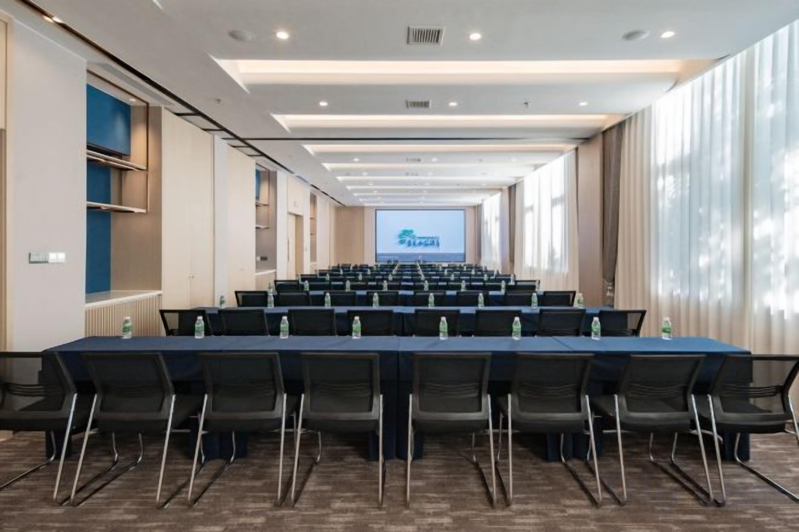 A conference room with a long table, chairs, and a projection screen at the front.