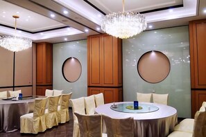 Un salón de conferencias con mesas redondas, sillas y una araña.