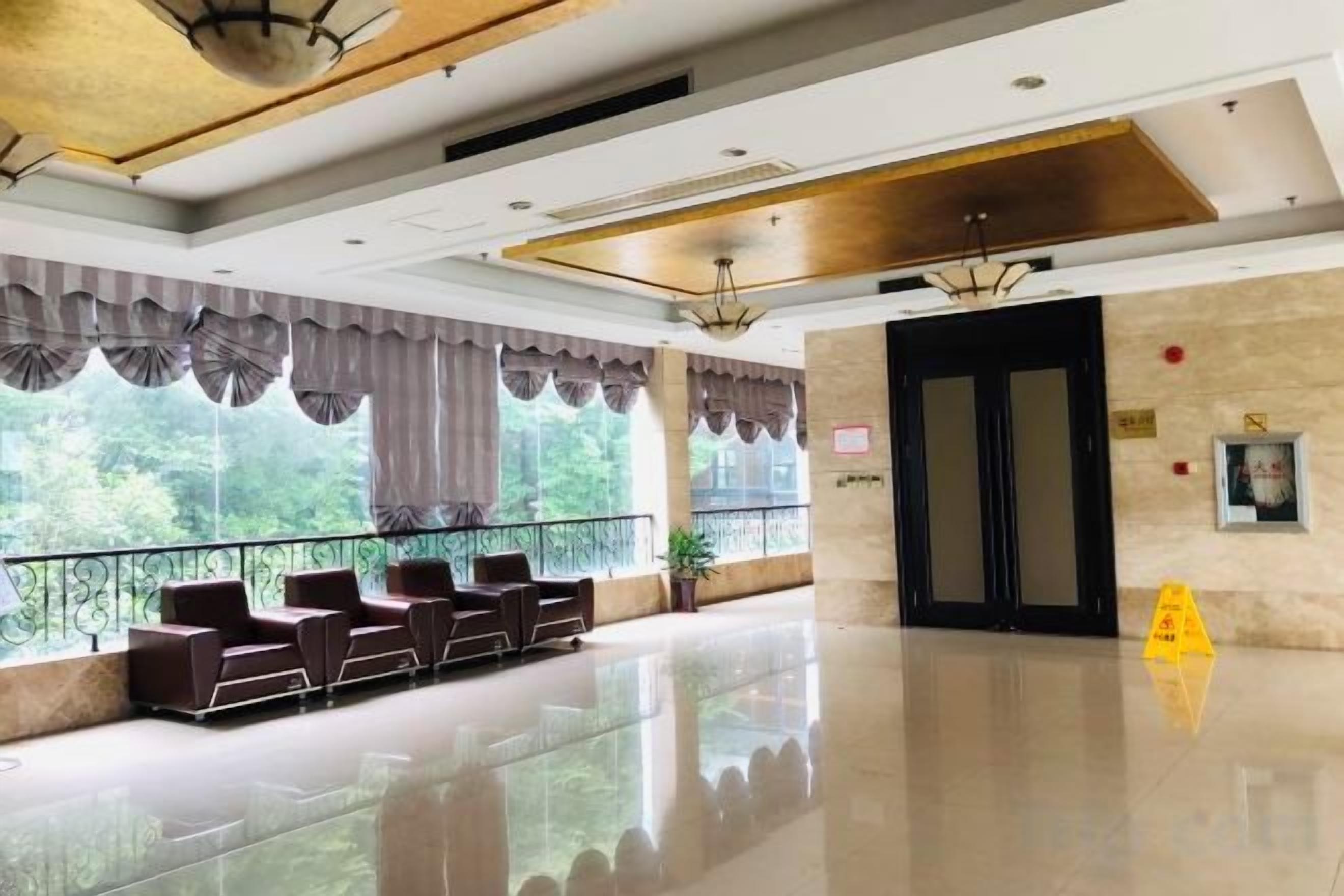 A hotel lobby with a reception desk, seating area, and large windows.