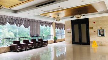 A hotel lobby with a reception desk, seating area, and large windows.
