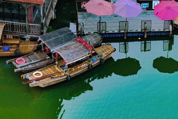 A traditional wooden boat docked at a pier with a reflection in the water. - Jingyuan Shuizhuang Hotel (Shanghai)