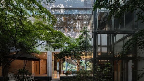 A modern building with a glass facade, outdoor seating area, and greenery. - Jingyuan Shuizhuang Hotel (Shanghai)