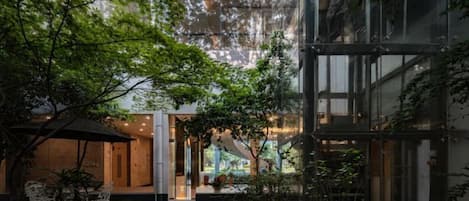 A modern building with a glass facade, a patio area with outdoor seating, and a view of the interior.