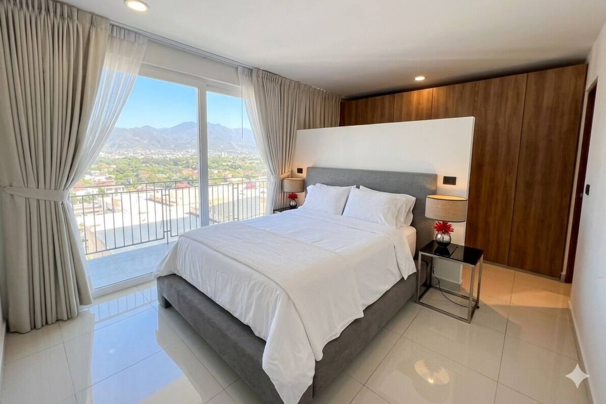 Una habitación de hotel moderna con una cama grande, un balcón y vistas a la ciudad.