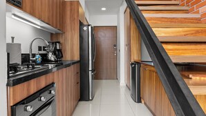 A modern kitchen with wooden cabinets, a stainless steel refrigerator, and a built-in oven. - Zoho Skies by Monyxbnb (Puerto Vallarta)