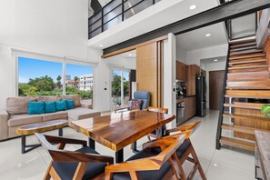 A modern interior with a dining area, sofa, kitchen, and a staircase. - Zoho Skies by Monyxbnb (Puerto Vallarta)