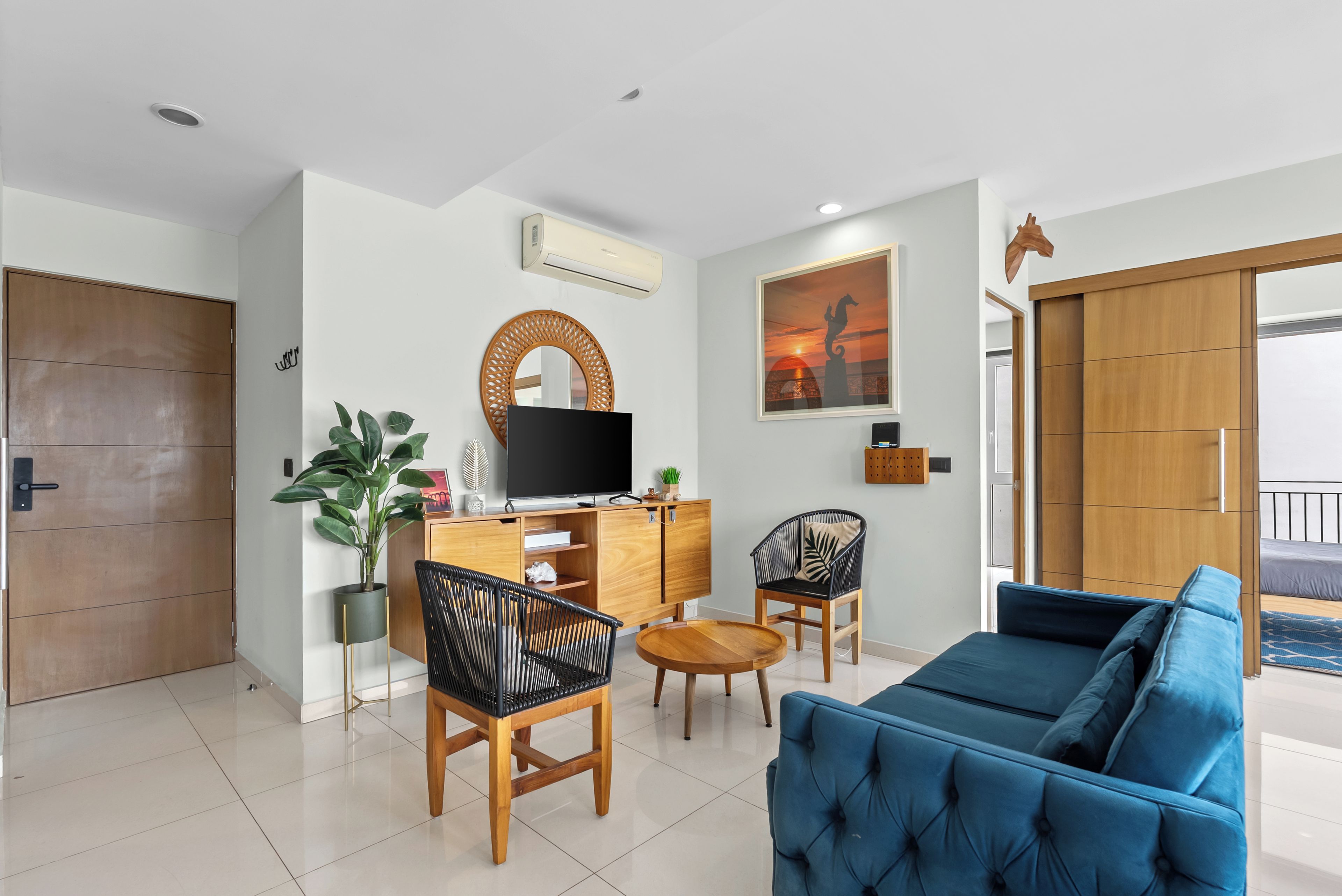 A modern living room with a sofa, chairs, a TV, a potted plant, and a wooden cabinet.