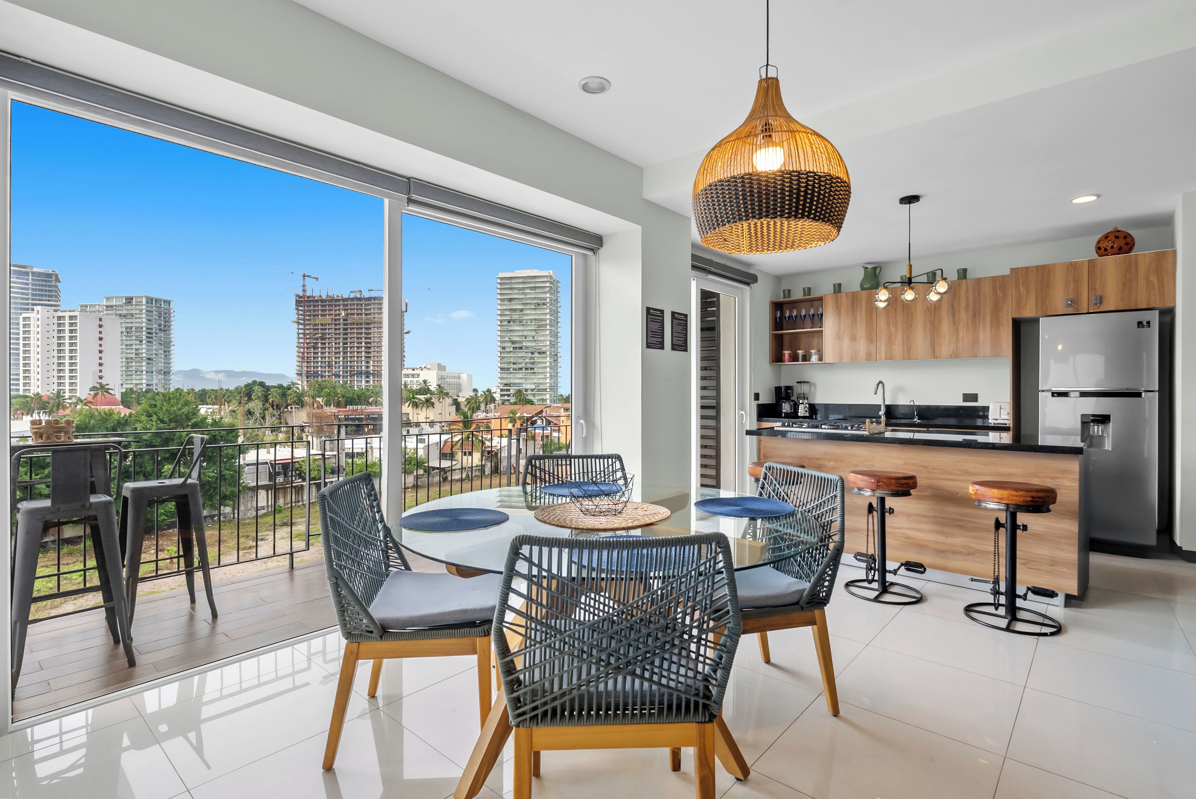A modern kitchen with a refrigerator, wooden cabinets, and a dining area with a round table and chairs.
