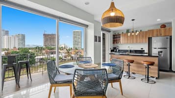 Una cocina moderna con refrigerador, armarios de madera y un comedor con mesa y sillas redondas.