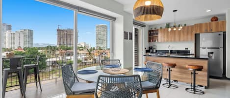A modern kitchen with a refrigerator, wooden cabinets, and a dining area with a round table and chairs.