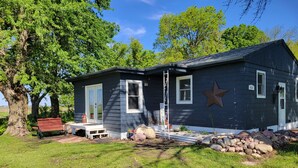 A single-story house with a dark exterior, a front porch, and a star decoration on the wall.
