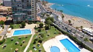 Un hotel costero con piscina, acceso a la playa y vistas al mar.