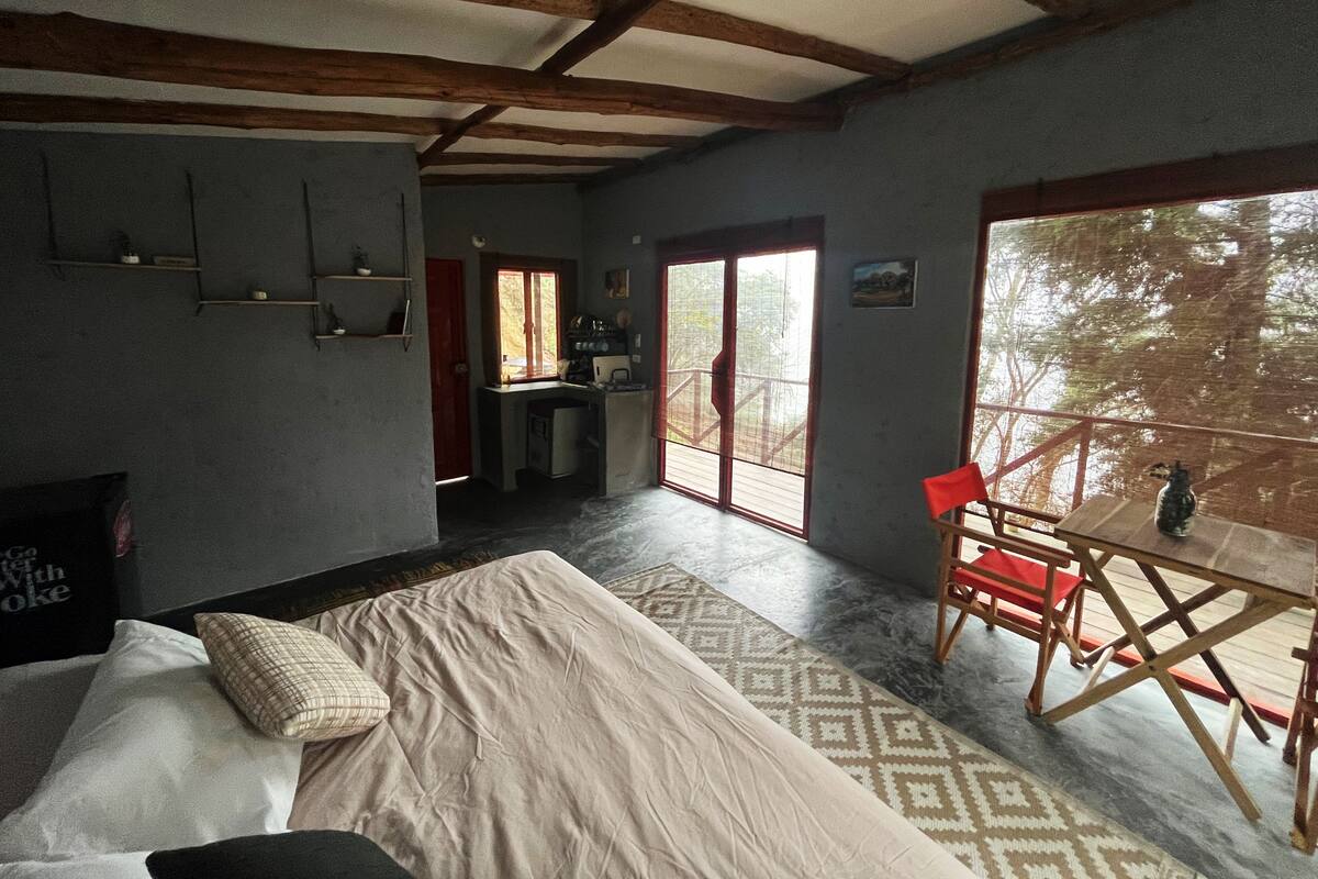 Een slaapkamer met een bed, een bureau, een stoel en een groot raam.